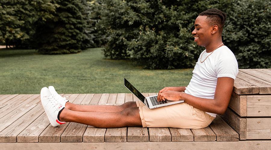 young black male student looking through transfer resources on laptop